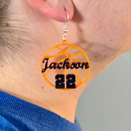 Personalized orange and black basketball earring with Jackson and number 22 being worn.