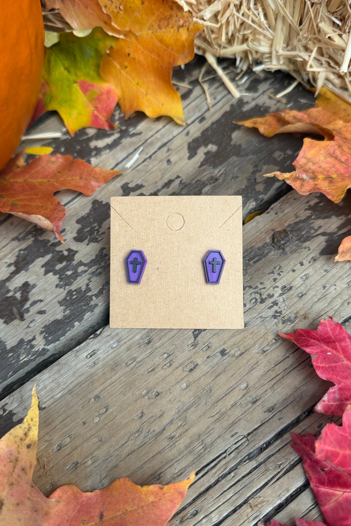 Purple coffin Halloween stud earrings styled with fall leaves