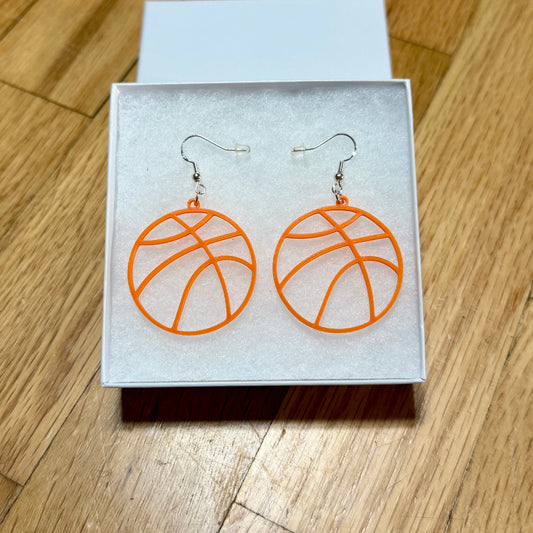 Pair of orange basketball earrings with open line design displayed in a jewelry box.