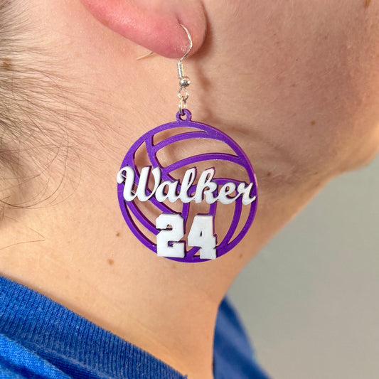 Personalized purple and white volleyball earring with Walker and number 24 being worn.