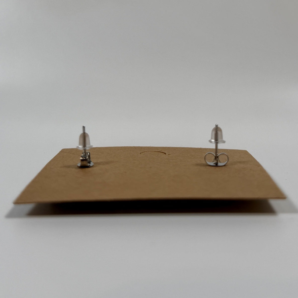 Back of stud earrings showing stainless steel posts with butterfly backs on a kraft earring card.
